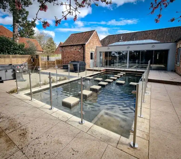 garden pond with glass balustrades around the edge with a house in the background