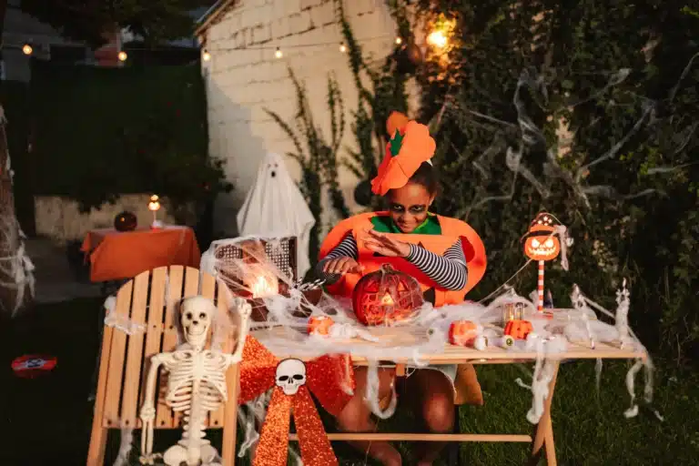 child dressed as a pumpkin on a balcony with spooky table decorations
