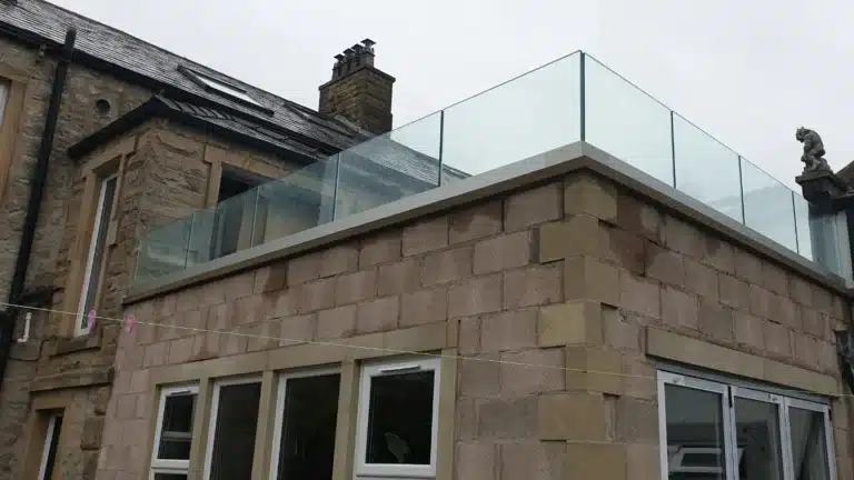 Aged stone building with a open part of roof encase in frameless glass balustrades