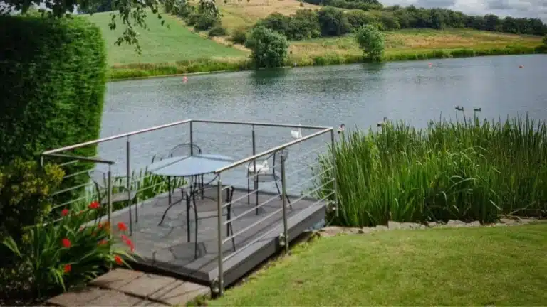 metal wire balustrade surrounding a garden furniture set by the side of a lake