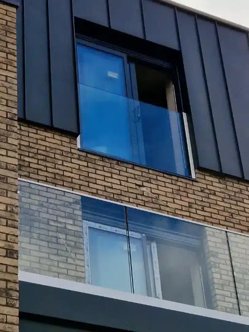 Tall brick building with glass double doors covered with juliet balconies