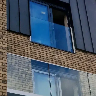 Tall brick building with glass double doors covered with juliet balconies